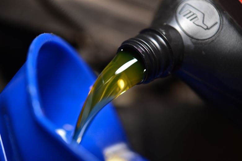 Technician pouring fresh engine oil