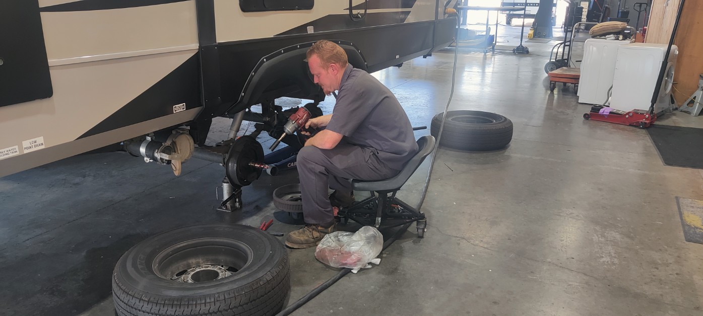 Giant RV technician servicing a trailer wheel hub and bearings